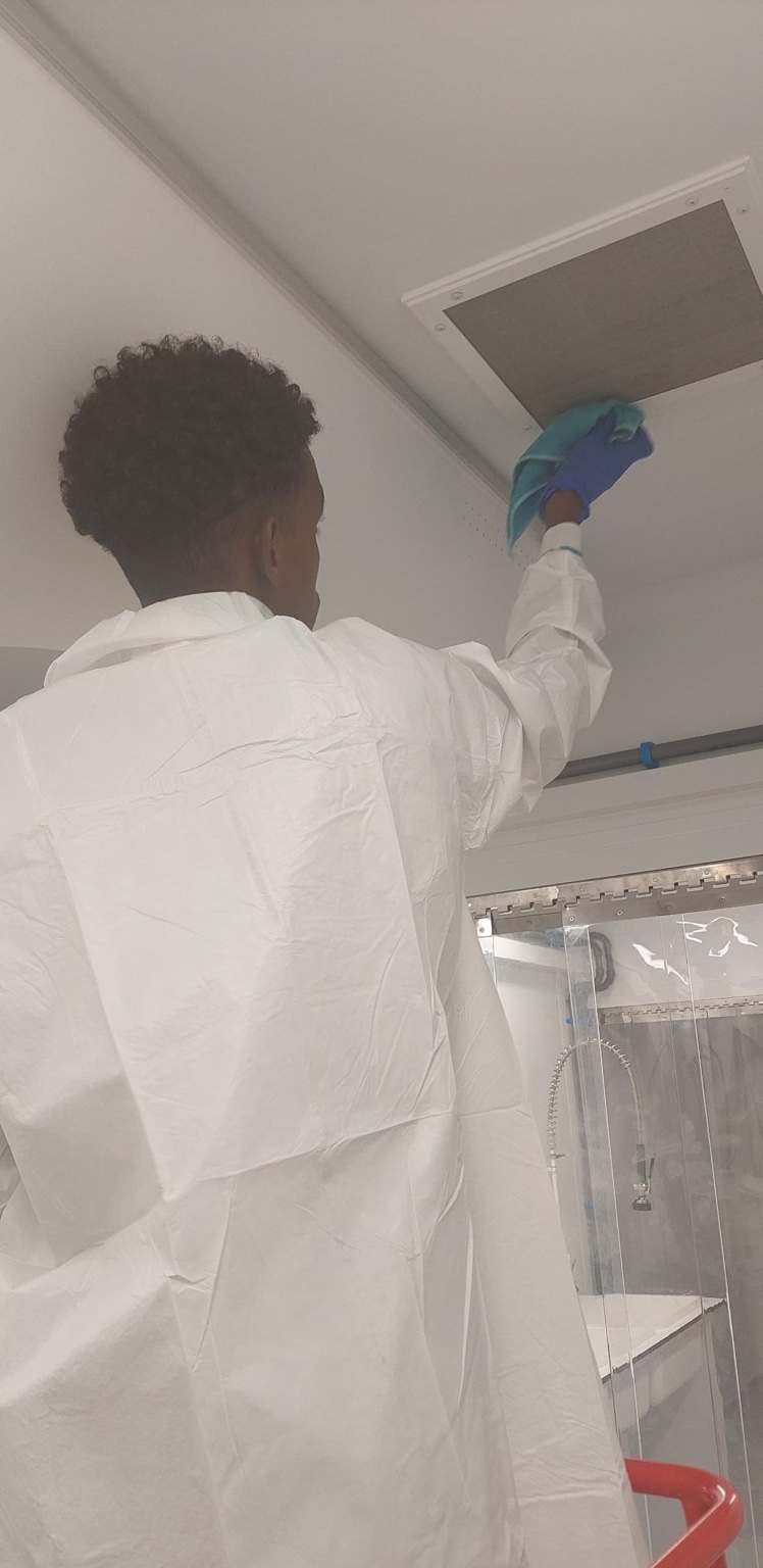 Technician cleaning an air vent with PPE